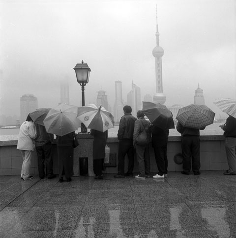 Pudong viewers with umbrellas overlooking the river photo Paul Maurer